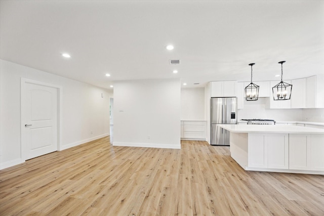 1935 Willow Rd, Wallis, TX 77485 - kitchen with white cabinetry, light countertops, light wood-type flooring, and stainless steel refrigerator with ice dispenser