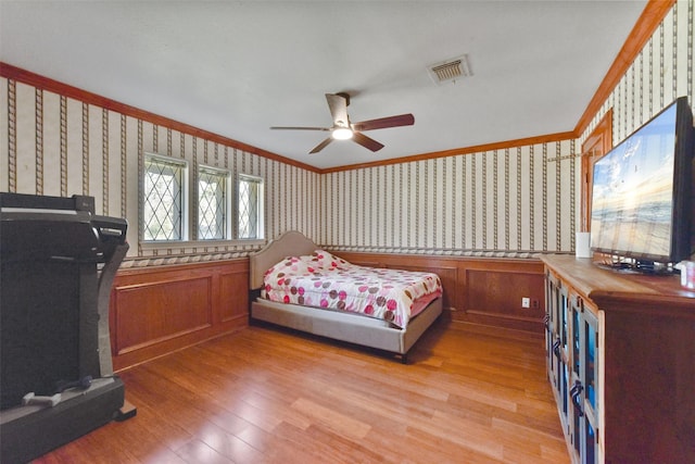 bedroom with crown molding, wallpapered walls, light wood-style flooring, and visible vents