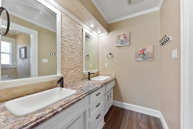full bath with a sink, baseboards, crown molding, and wood finished floors