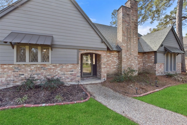 view of front of property with brick siding, a chimney, and a front yard