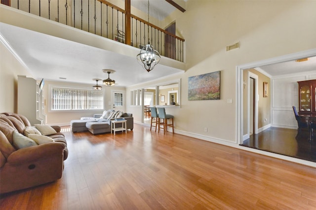 living room with visible vents, crown molding, wood finished floors, baseboards, and a notable chandelier