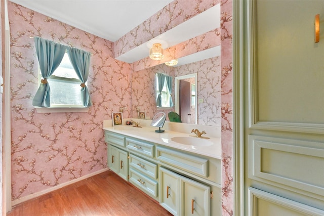bathroom featuring a sink, baseboards, double vanity, and wood finished floors