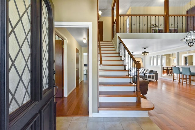 foyer with stairway, baseboards, a ceiling fan, and light wood finished floors