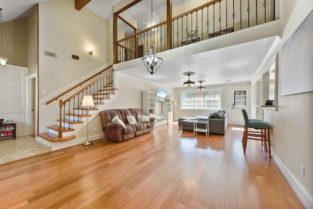 living room featuring an inviting chandelier, stairs, a high ceiling, and visible vents