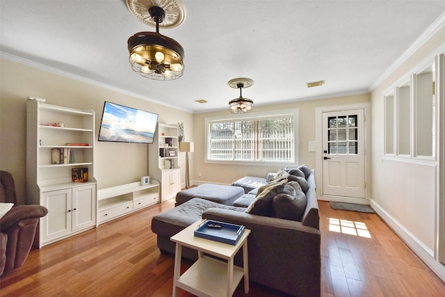 living room with ornamental molding, wood finished floors, and visible vents