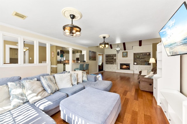 living area featuring a fireplace, wood finished floors, and visible vents