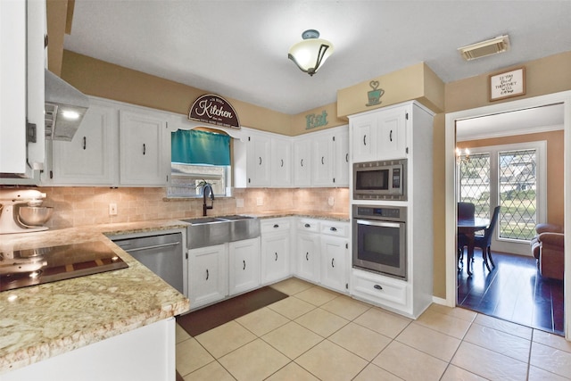 kitchen featuring light tile patterned flooring, a sink, stainless steel appliances, white cabinetry, and visible vents