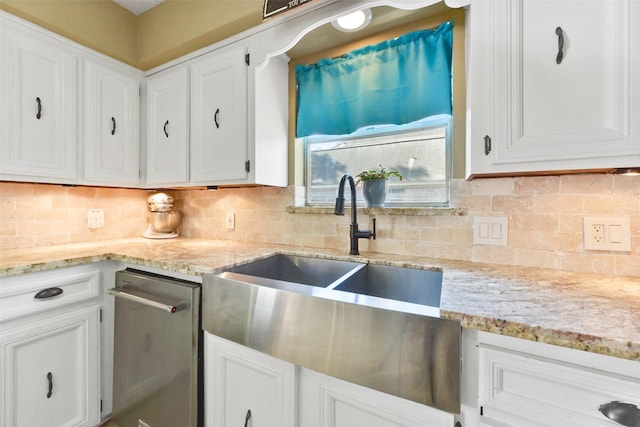 kitchen with light stone counters, a sink, decorative backsplash, and white cabinets