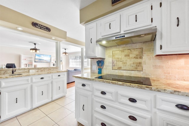 kitchen with a sink, black electric cooktop, under cabinet range hood, and white cabinets
