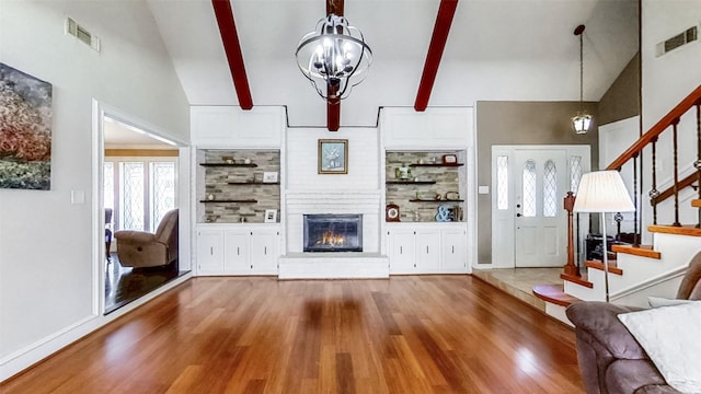 living room featuring a notable chandelier, stairs, wood finished floors, and visible vents