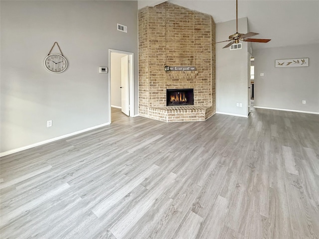 unfurnished living room featuring a brick fireplace, high vaulted ceiling, a ceiling fan, visible vents, and baseboards