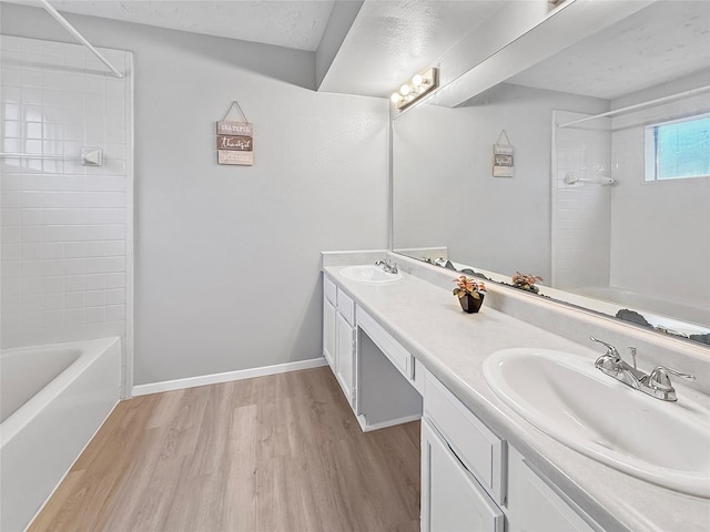 full bathroom featuring shower / washtub combination, a sink, double vanity, and wood finished floors