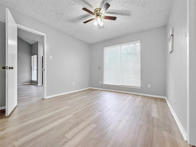 unfurnished room featuring baseboards, a ceiling fan, a textured ceiling, and light wood finished floors