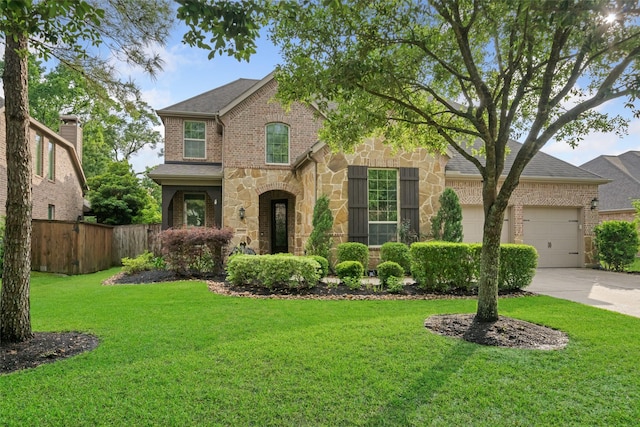 view of front facade with a front yard, driveway, stone siding, an attached garage, and fence
