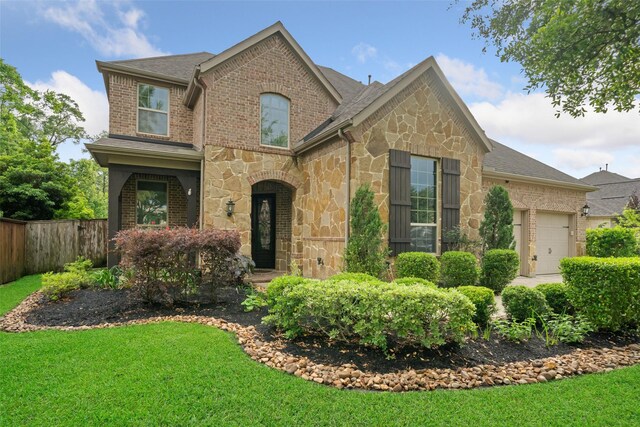 view of front of house with fence, a garage, a front lawn, and stone siding
