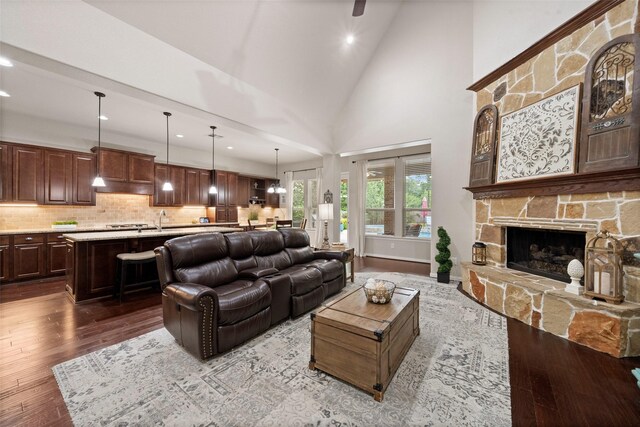 living room with dark wood finished floors, recessed lighting, a fireplace, and high vaulted ceiling