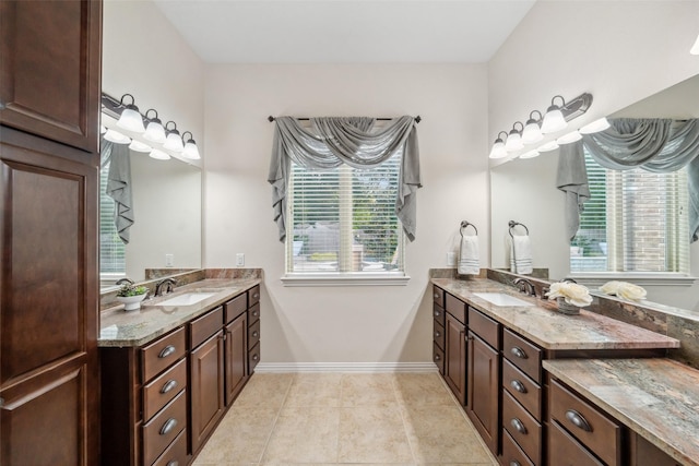 bathroom featuring two vanities, plenty of natural light, and a sink