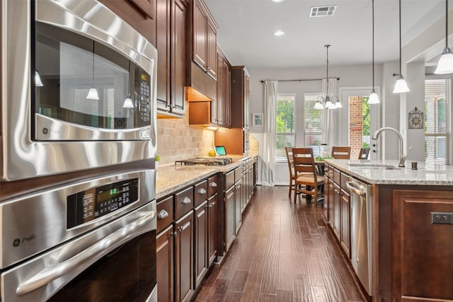 kitchen featuring appliances with stainless steel finishes, dark wood-style flooring, a sink, visible vents, and a notable chandelier