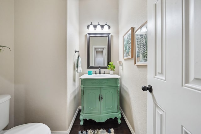 half bath featuring vanity, toilet, and baseboards