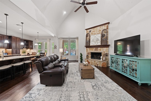 living area featuring dark wood-style floors, high vaulted ceiling, a ceiling fan, a stone fireplace, and visible vents