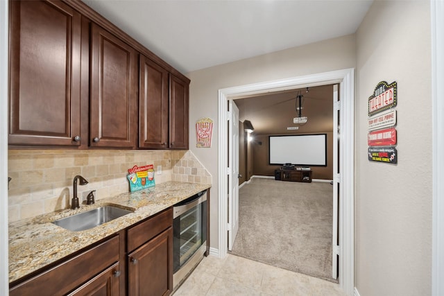 kitchen with light stone counters, decorative backsplash, a sink, baseboards, and light tile patterned flooring