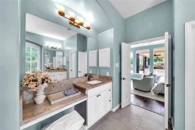bathroom featuring baseboards, lofted ceiling, tile patterned flooring, and vanity