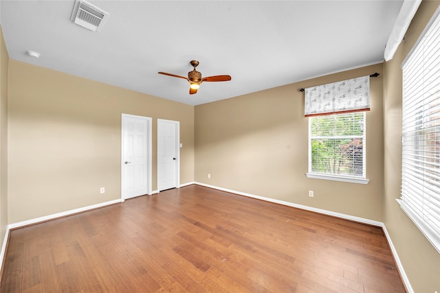 spare room with baseboards, visible vents, and wood finished floors