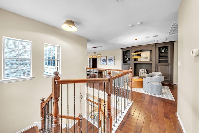 corridor with baseboards, dark wood-style flooring, visible vents, and an upstairs landing