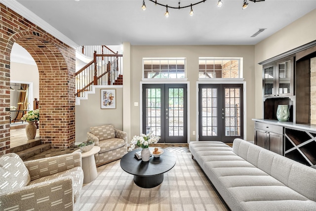 living room featuring french doors, brick wall, stairway, and visible vents