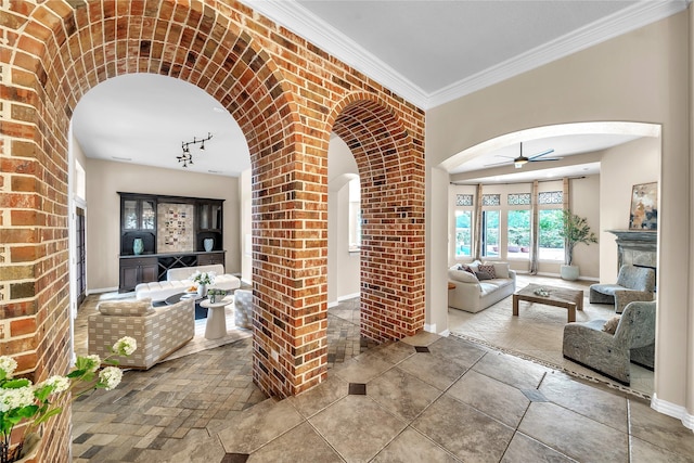 interior space with crown molding, ceiling fan, track lighting, arched walkways, and baseboards