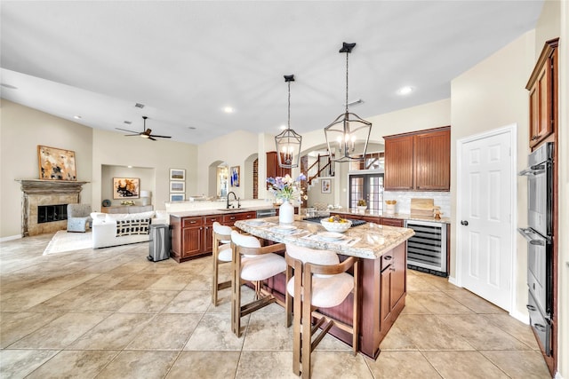 kitchen featuring stainless steel double oven, beverage cooler, arched walkways, a peninsula, and open floor plan