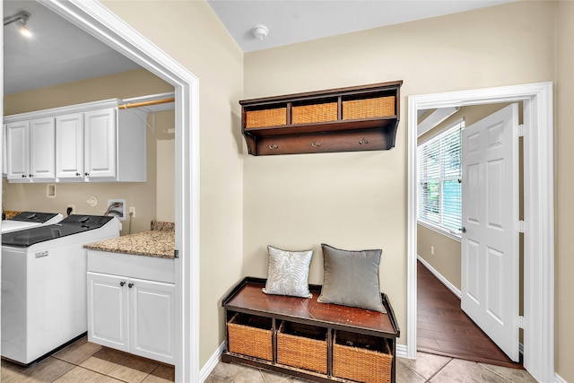 mudroom featuring light tile patterned floors, baseboards, and washing machine and dryer