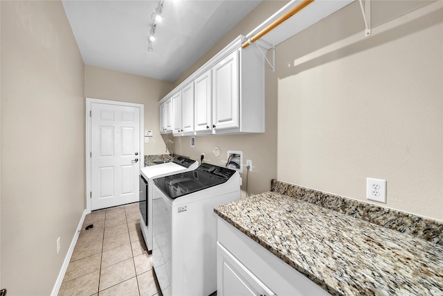 laundry area with cabinet space, rail lighting, baseboards, light tile patterned floors, and washing machine and dryer