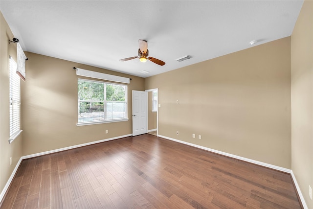 unfurnished room featuring baseboards, a ceiling fan, dark wood-type flooring, and visible vents