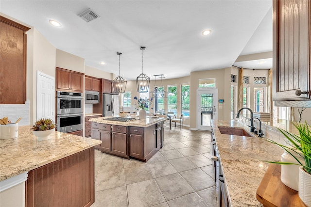 kitchen featuring light stone countertops, appliances with stainless steel finishes, a sink, and visible vents