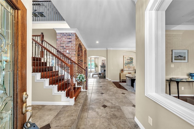entryway featuring arched walkways, stairs, baseboards, visible vents, and ornamental molding
