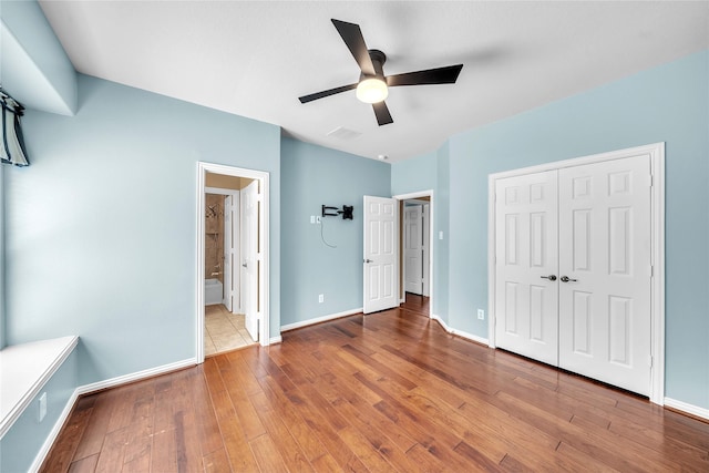 unfurnished bedroom with ceiling fan, baseboards, visible vents, hardwood / wood-style flooring, and a closet