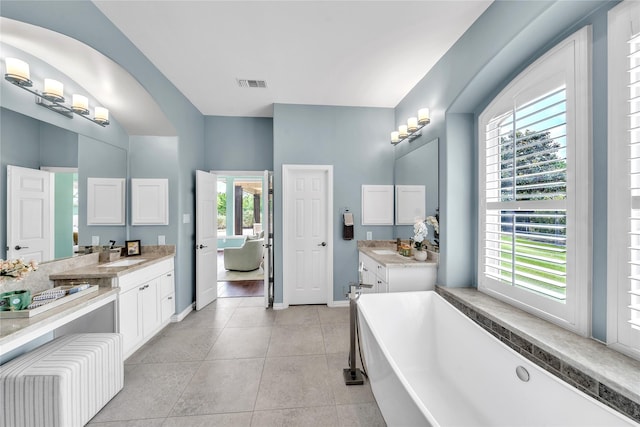 bathroom featuring a freestanding bath, a sink, tile patterned floors, baseboards, and visible vents
