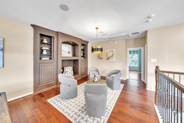 living area featuring baseboards, wood-type flooring, attic access, and visible vents