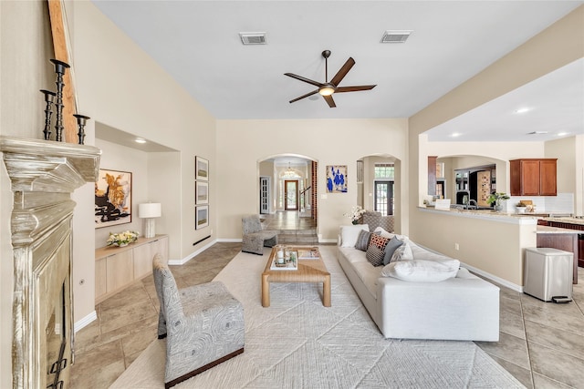 living area featuring arched walkways, ceiling fan, visible vents, and light tile patterned floors