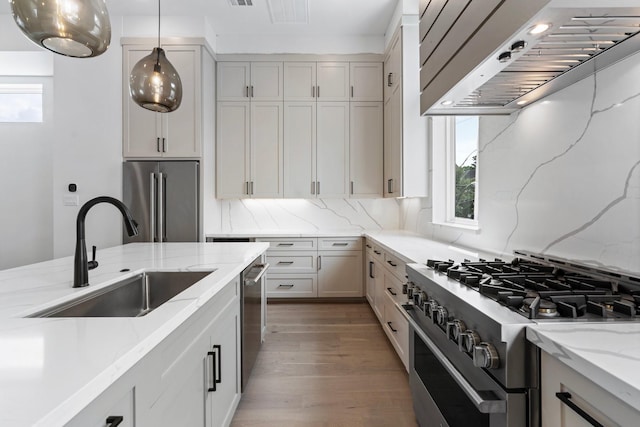 4705 Gibson St, Houston, TX 77007 - kitchen with premium appliances, a sink, wall chimney range hood, light stone countertops, and wood finished floors