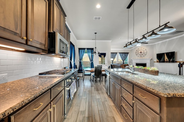717 Willowbranch Ln, Midlothian, TX 76065 - kitchen with visible vents, ornamental molding, open floor plan, a sink, and appliances with stainless steel finishes
