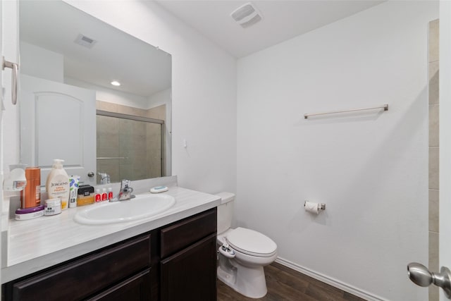 bathroom with wood finished floors, a shower stall, toilet, vanity, and baseboards
