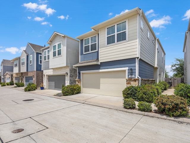 multi unit property featuring a garage, a residential view, stone siding, and concrete driveway