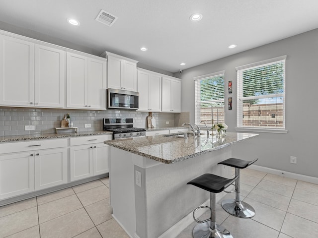 kitchen featuring visible vents, tasteful backsplash, a sink, stainless steel appliances, and white cabinetry