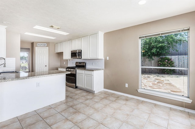 1918 N Everglades Dr, Deer Park, TX 77536 - kitchen with light stone countertops, decorative backsplash, stainless steel appliances, white cabinets, and a sink