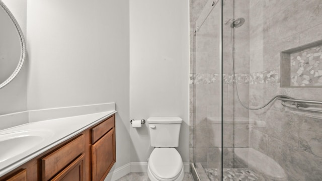 full bathroom with baseboards, toilet, a tile shower, and vanity