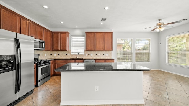 kitchen featuring light tile patterned floors, a sink, appliances with stainless steel finishes, and decorative backsplash