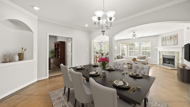 dining area with recessed lighting, a fireplace, ornamental molding, arched walkways, and ceiling fan with notable chandelier
