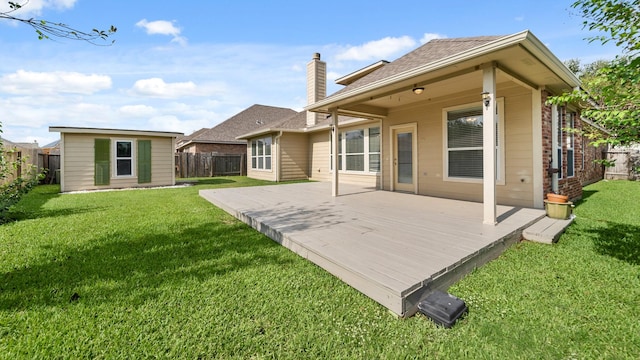 rear view of house with an outdoor structure, a yard, a wooden deck, and a fenced backyard